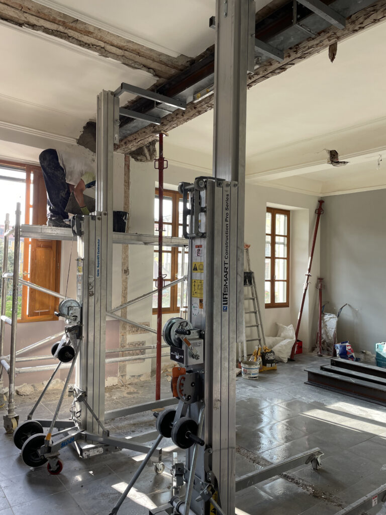 Perspective sur les deux lève-matériaux, échafaudage et renfort acier continu ; mortier de scellement visible en extrémité.